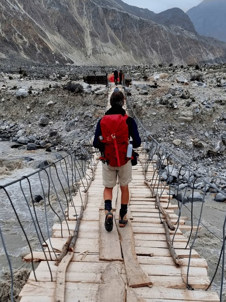 Trekker crossing bridge in Northern Pakistan mountains
